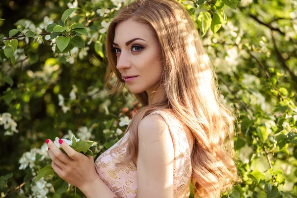 Bela jovem mulher em um vestido de verão perto de árvores florescentes — Fotografia de Stock