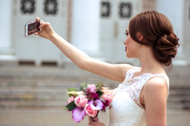 muhteşem gelin moda makyaj ve saç bir lüks gelinlik ile kendini fotoğraf üstünde hareket eden telefon yapar.