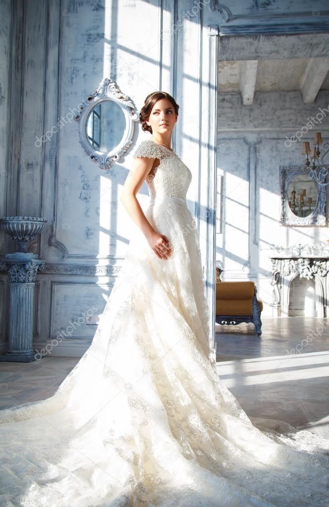 Photo of a beautiful brunette bride in a luxurious wedding dress in elegant expensive interior