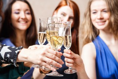 Neşeli kızlar partide şampanya bardaklarını tokuşturuyor.