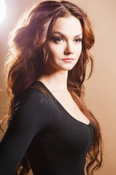 Close-up portrait of beautiful sexy young woman with long brown hair over brown background — Stock Photo, Image