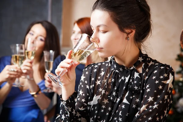 Портрет красивой молодой женщины с бокалом шампанского, празднующей Новый год с друзьями — стоковое фото