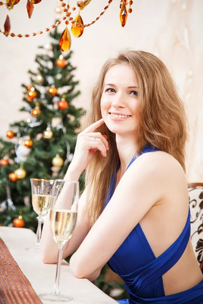 Όμορφη νεαρή ξανθιά γυναίκα που κάθεται στο τραπέζι με το ποτήρι σαμπάνιας — Φωτογραφία Αρχείου