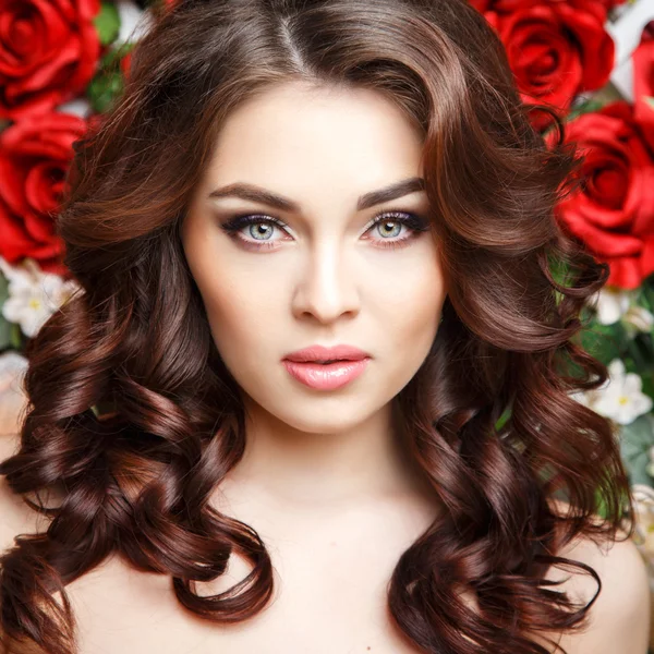 Ritratto ravvicinato di bella giovane donna con un trucco perfetto e uno stile di capelli con fiori nei capelli — Foto Stock