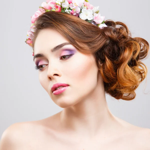 Retrato de cerca de una hermosa mujer joven con maquillaje perfecto y peinado con flores en el cabello — Foto de Stock