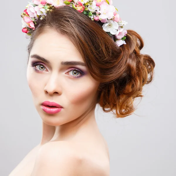 Retrato de cerca de una hermosa mujer joven con maquillaje perfecto y peinado con flores en el cabello — Foto de Stock