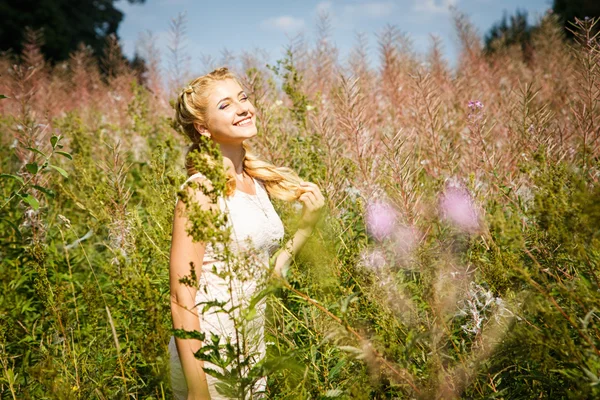 Bastante joven rubia en el campo de flores en un verano — Foto de Stock