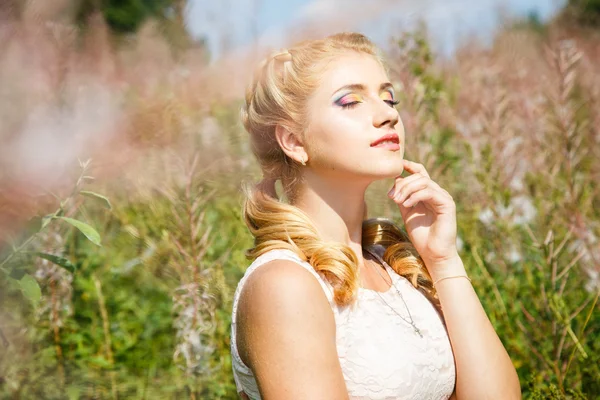 Bastante joven rubia en el campo de flores en un verano — Foto de Stock