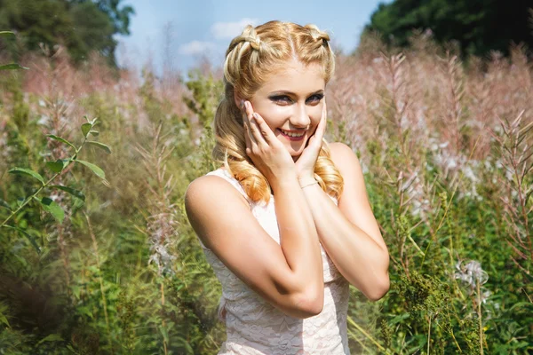 Bastante joven rubia en el campo de flores en un verano — Foto de Stock