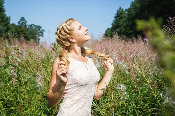 Pretty young blonde girl on blossoming field in a summer — Stock Photo, Image