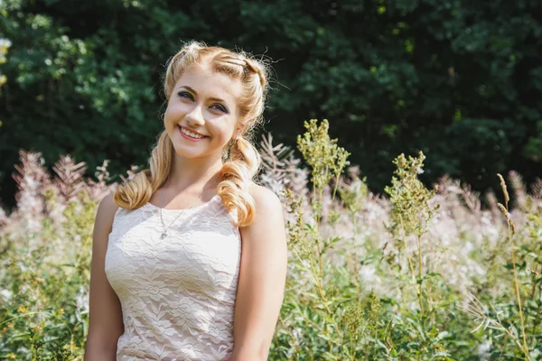 Hübsche junge blonde Mädchen auf blühenden Feld in einem Sommer — Stockfoto