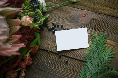 Florist workplace: visit card and flowers and accessories on a vintage wooden table. soft focus