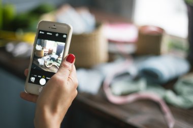 Florist at work: pretty young blond woman making photo on her mobile phone (smart phone)