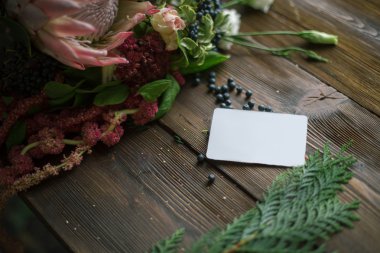 Florist workplace: visit card and flowers and accessories on a vintage wooden table. soft focus