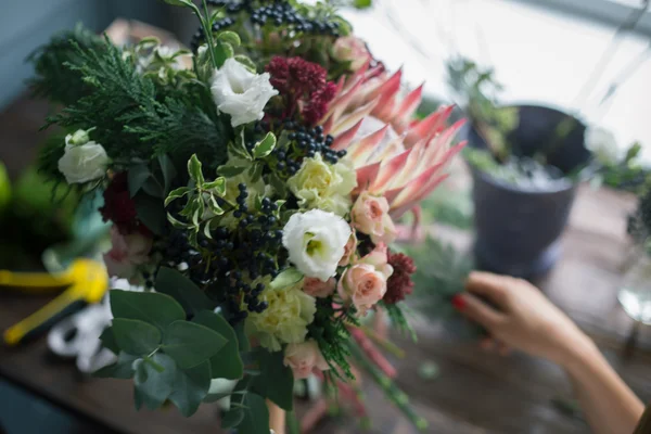 Çiçekçi işyeri: çiçek ve aksesuarları bir vintage ahşap masa üzerinde. yumuşak odak — Stok fotoğraf