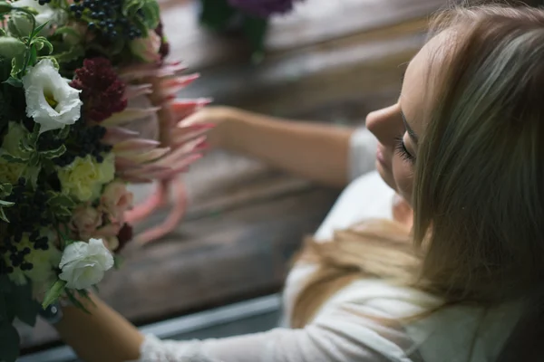 Florista en el trabajo: mujer rubia bastante joven haciendo ramo moderno de moda de diferentes flores — Foto de Stock