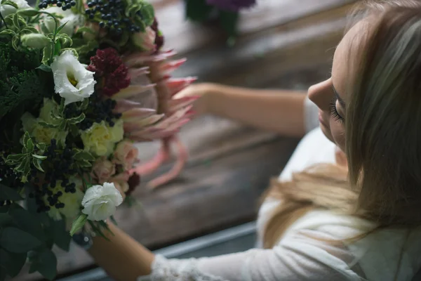 Флорист на роботі: красива молода блондинка робить моду сучасним букетом з різних квітів — стокове фото
