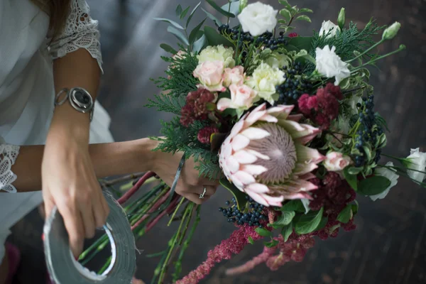 Floristin bei der Arbeit: Hübsche junge blonde Frau macht Mode modernen Strauß aus verschiedenen Blumen — Stockfoto