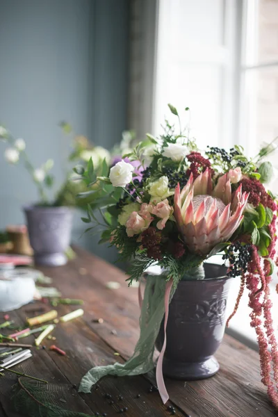 Local de trabalho florista: flores e acessórios em uma mesa de madeira vintage. foco suave — Fotografia de Stock