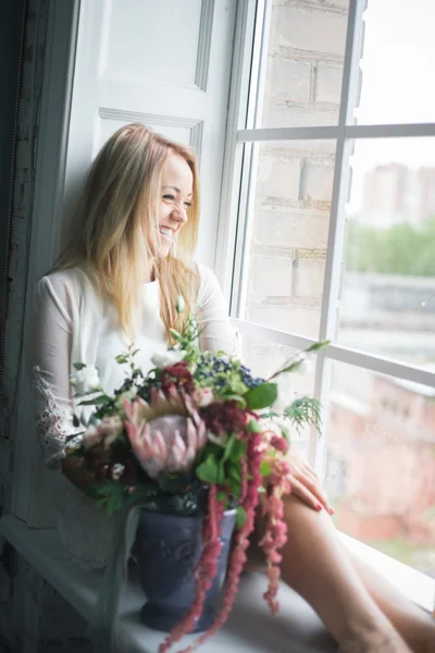 Florista en el trabajo: mujer rubia bastante joven haciendo ramo moderno de moda de diferentes flores — Foto de Stock