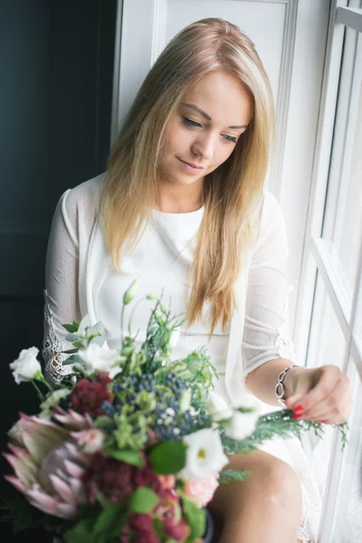 Florist at work: pretty young blond woman making fashion modern bouquet of different flowers — Stock Photo, Image