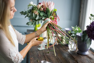 İş yerinde çiçekçi: genç ve güzel sarışın kadın moda modern buket farklı çiçek yapma