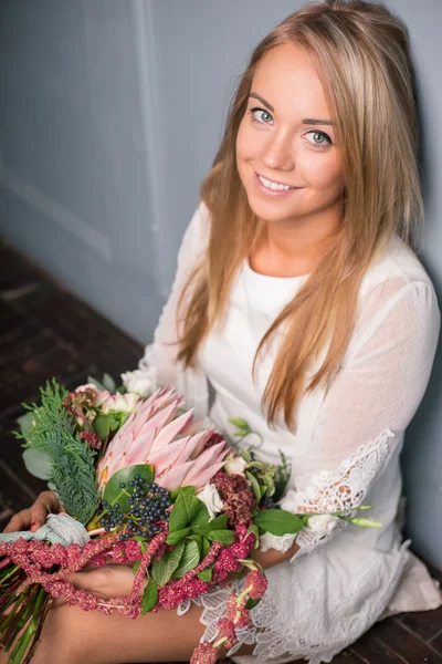 Florista en el trabajo: mujer rubia bastante joven haciendo ramo moderno de moda de diferentes flores — Foto de Stock