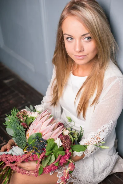 Florista en el trabajo: mujer rubia bastante joven haciendo ramo moderno de moda de diferentes flores — Foto de Stock