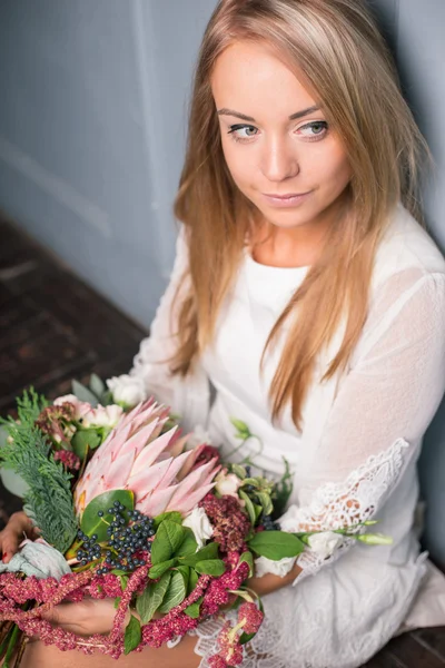 Florista en el trabajo: mujer rubia bastante joven haciendo ramo moderno de moda de diferentes flores — Foto de Stock