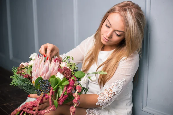 Florista en el trabajo: mujer rubia bastante joven haciendo ramo moderno de moda de diferentes flores — Foto de Stock