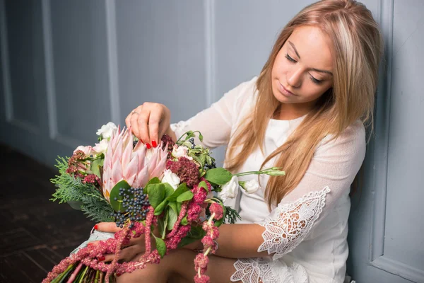 Florista en el trabajo: mujer rubia bastante joven haciendo ramo moderno de moda de diferentes flores — Foto de Stock