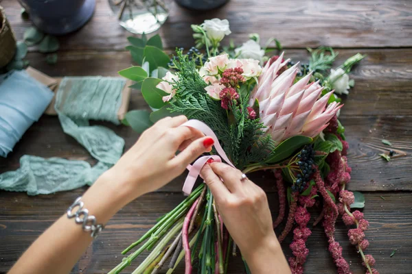 Florista no trabalho: mulher loira muito jovem fazendo moda buquê moderno de flores diferentes — Fotografia de Stock