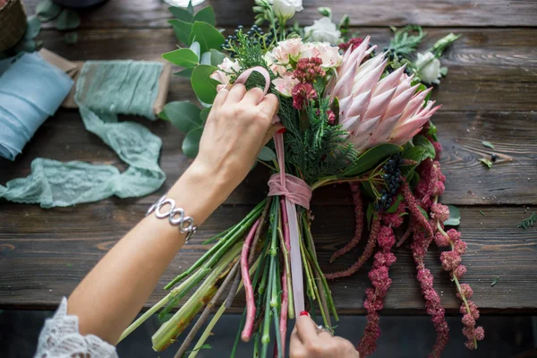 Florista no trabalho: mulher loira muito jovem fazendo moda buquê moderno de flores diferentes — Fotografia de Stock