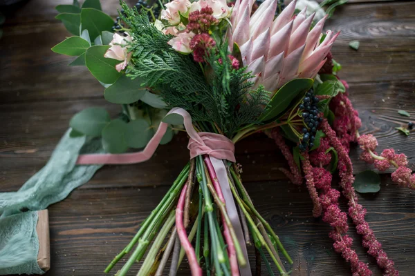 Local de trabalho florista: flores e acessórios em uma mesa de madeira vintage. foco suave — Fotografia de Stock