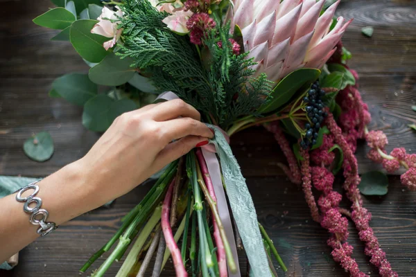 Floristin bei der Arbeit: Hübsche junge blonde Frau macht Mode modernen Strauß aus verschiedenen Blumen — Stockfoto