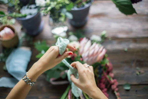 Florista no trabalho: mulher loira muito jovem fazendo moda buquê moderno de flores diferentes — Fotografia de Stock