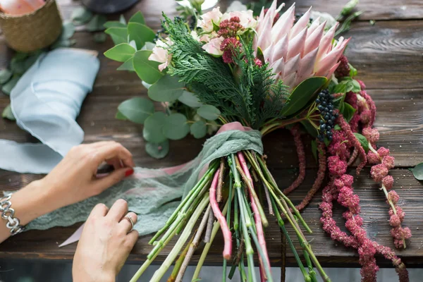 Florista no trabalho: mulher loira muito jovem fazendo moda buquê moderno de flores diferentes — Fotografia de Stock