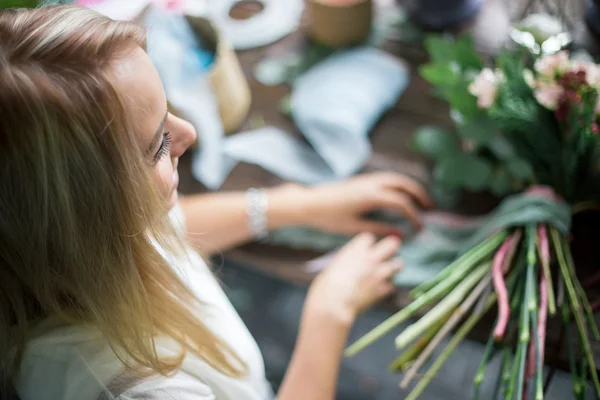 Florista en el trabajo: mujer rubia bastante joven haciendo ramo moderno de moda de diferentes flores — Foto de Stock