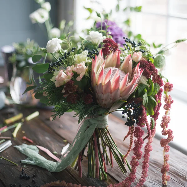 Local de trabalho florista: flores e acessórios em uma mesa de madeira vintage. foco suave — Fotografia de Stock