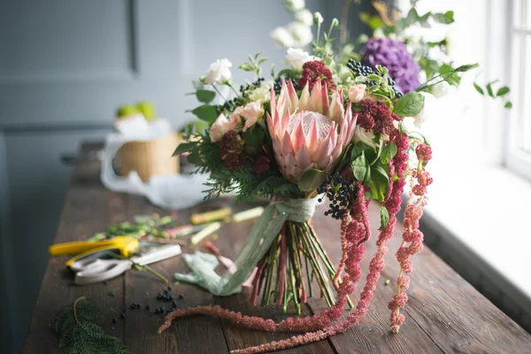 Bloemist werkplek: bloemen en accessoires op een vintage houten tafel. Soft Focus Sea... — Stockfoto