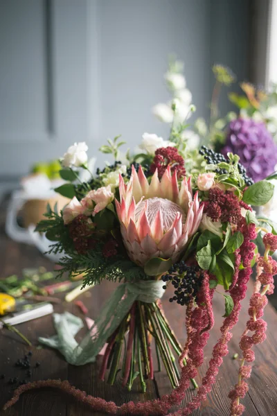 Local de trabalho florista: flores e acessórios em uma mesa de madeira vintage. foco suave — Fotografia de Stock