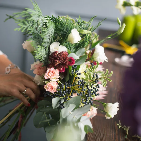 Florist at work: pretty young blond woman making fashion modern bouquet of different flowers — Stock Photo, Image