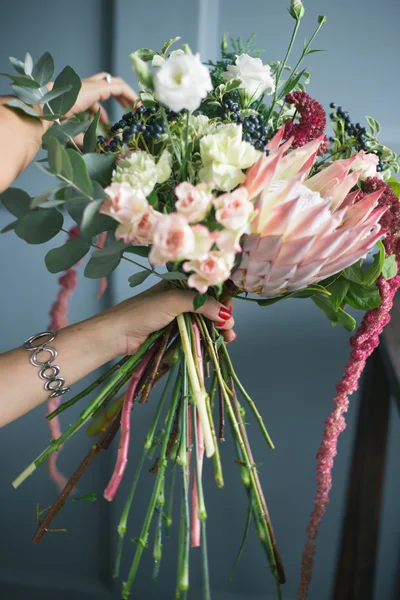 Florista no trabalho: mulher loira muito jovem fazendo moda buquê moderno de flores diferentes — Fotografia de Stock