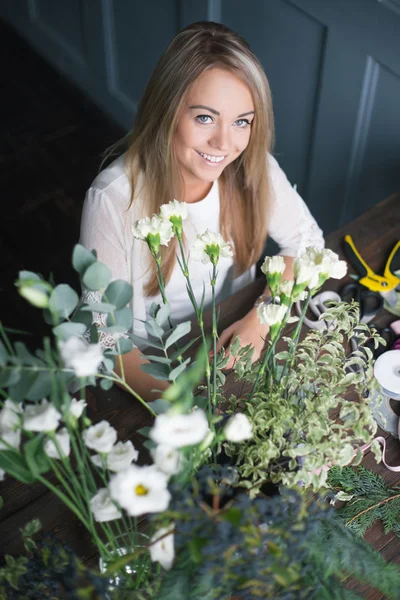 Florista en el trabajo: mujer rubia bastante joven haciendo ramo moderno de moda de diferentes flores — Foto de Stock