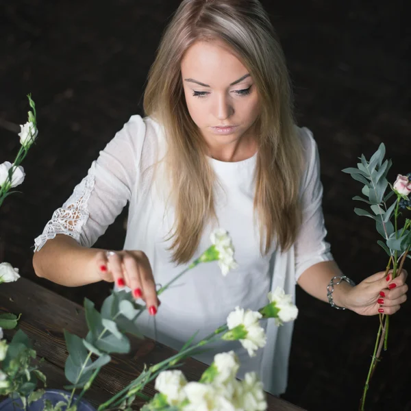 Florista en el trabajo: mujer rubia bastante joven haciendo ramo moderno de moda de diferentes flores — Foto de Stock