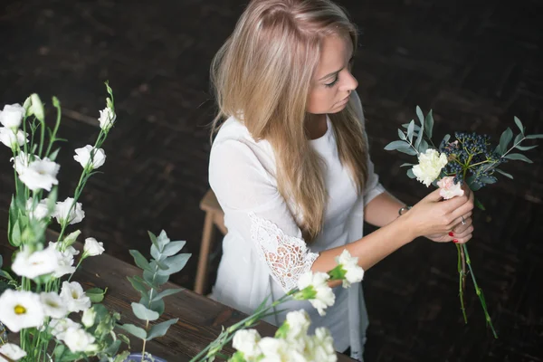 Florista no trabalho: mulher loira muito jovem fazendo moda buquê moderno de flores diferentes — Fotografia de Stock