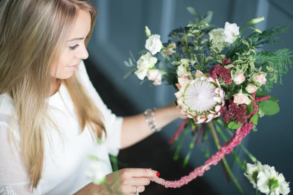 Florista no trabalho: mulher loira muito jovem fazendo moda buquê moderno de flores diferentes — Fotografia de Stock