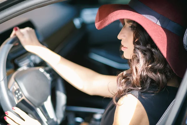 Nahaufnahme Porträt einer wunderschönen jungen brünetten Frau, die ein teures Auto fährt — Stockfoto