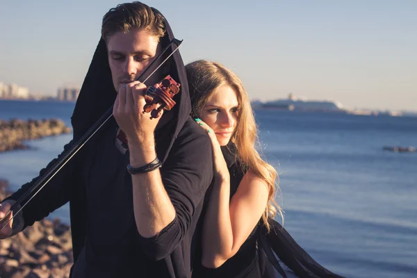 Hermosa pareja violinista y joven mujer juntos cerca de la bahía del mar — Foto de Stock