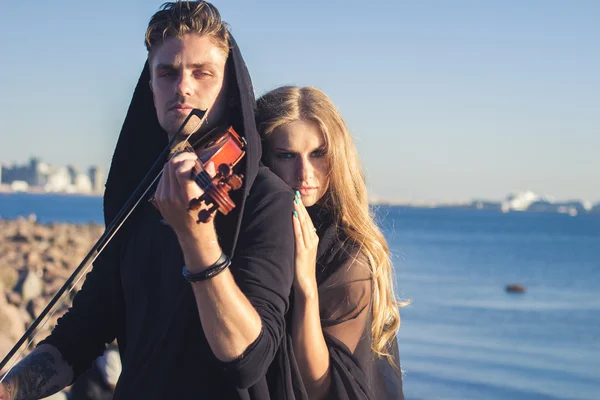 Hermosa pareja violinista y joven mujer juntos cerca de la bahía del mar — Foto de Stock